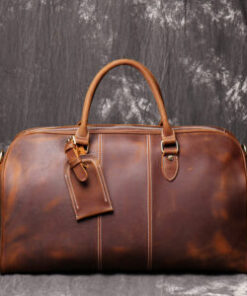 A brown leather duffel bag for travel with easy carry handles and a zipper.